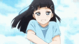 a little girl with black hair and blue eyes is wearing a blue shirt and standing with her arms crossed .