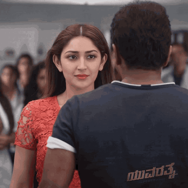a man and a woman are looking at each other and the man is wearing a shirt that says ' yuvarsh '