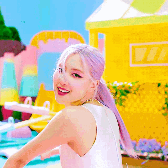 a woman with purple hair is smiling in front of a yellow house .