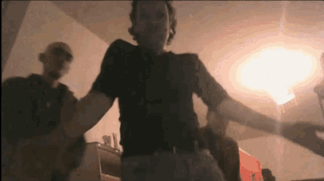 a man in a black shirt is dancing in a room with other people