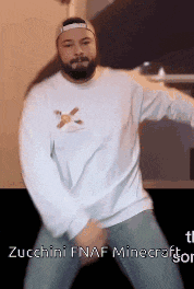a man with a beard is wearing a white sweater and a baseball cap and is dancing .