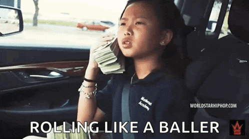 a little girl is sitting in the back seat of a car holding a pile of money .