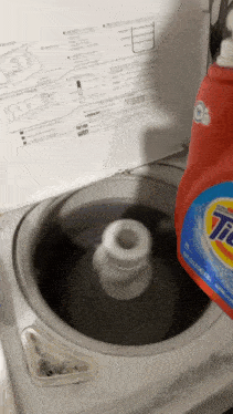 a bottle of tide laundry detergent being poured into a washing machine
