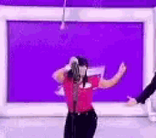a woman is dancing in front of a purple wall .