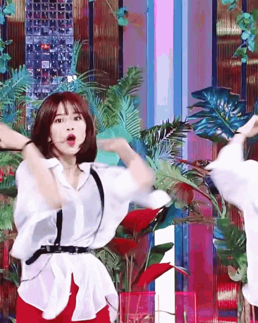 a woman in a white shirt and red shorts is dancing