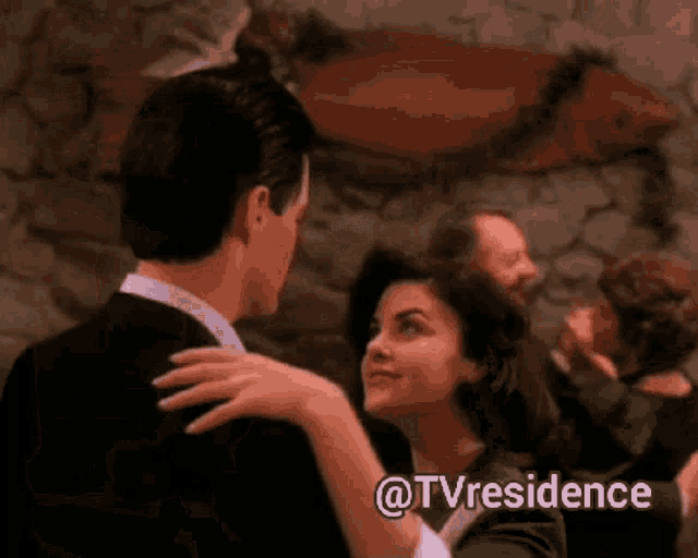 a man and a woman are dancing in front of a stone wall with the words @tvresidence above them