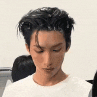 a close up of a man 's face with his eyes closed and his hair in a bun .