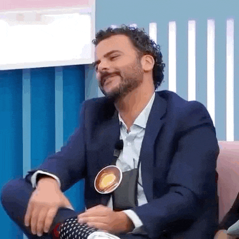 a man in a suit and tie is sitting in a chair and laughing .