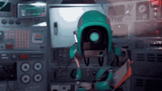 a robot with a camera on its head is standing in a room with a control panel .
