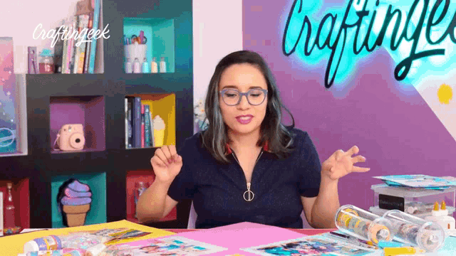 a woman sitting at a table with craftinggeek written on the wall