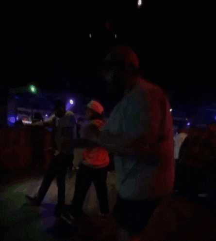 a man in a red shirt is dancing in front of a crowd