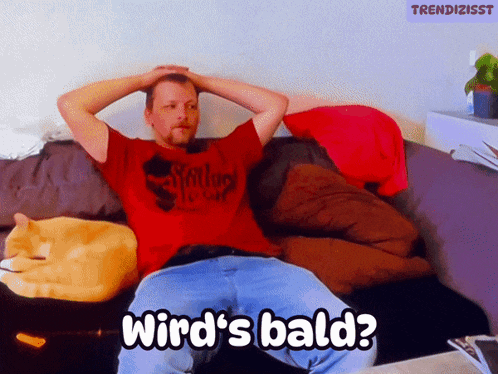 a man in a red shirt is sitting on a couch with his hands on his head and the words wird 's bald above him