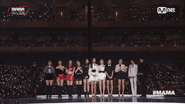 a group of women stand on a stage in front of a mnet sign