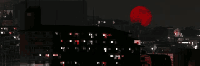 a full red moon is rising over a city at night