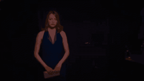 a woman in a blue dress is standing in the dark .