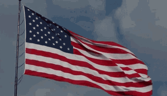 a red and white striped american flag is waving in the wind .