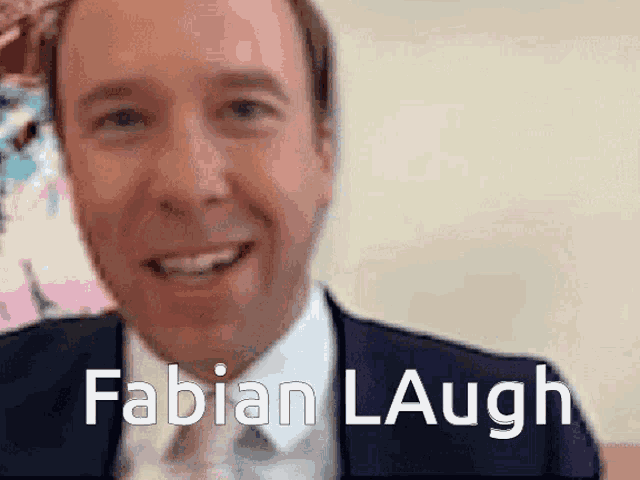 a man in a suit and tie is smiling with the words fabian laugh behind him .