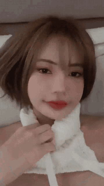 a woman with short brown hair is wearing a white top