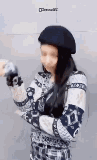 a woman wearing a black beret and a plaid shirt is standing in front of a wall .