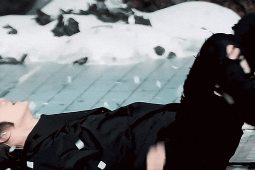 a person in a black suit is laying on their stomach