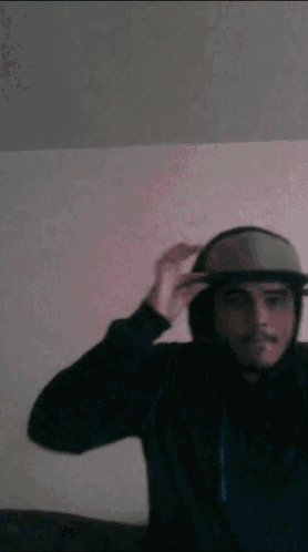 a man wearing a hat and a hoodie is adjusting his hat