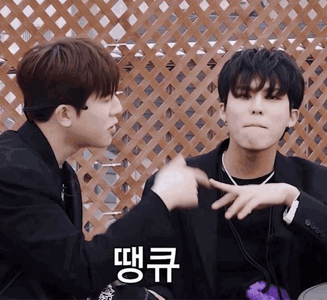 two young men are sitting next to each other and one of them has a foreign language written on his face
