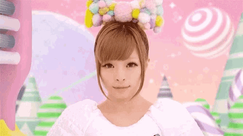 a woman is wearing a colorful headband and smiling in front of a pink background .