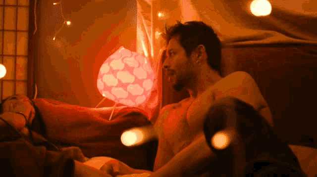 a man and a woman are laying on a bed with a lamp behind them