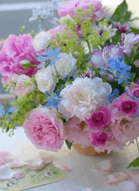 a bouquet of pink and white flowers in a vase on a table with petals on the table