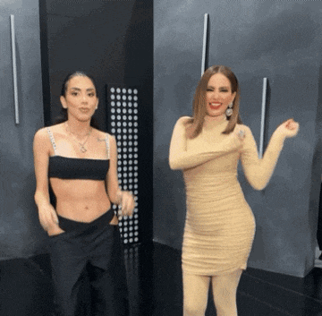 a woman in a crop top and a woman in a dress dancing