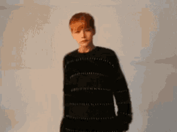 a young man with red hair is wearing a black sweater .