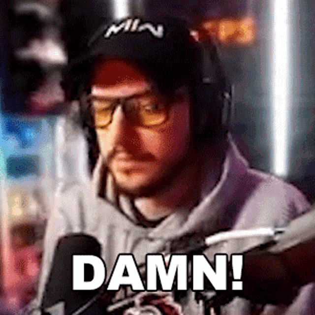 a man wearing headphones and a hat says damn