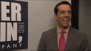 a man in a suit and tie stands in front of a sign that says er inc pany