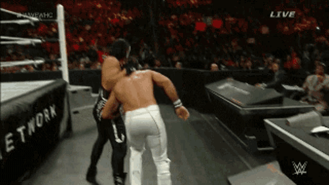 two wrestlers are fighting in a ring with a sign that says network in the background