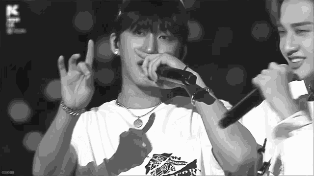 a black and white photo of a man singing into a microphone .