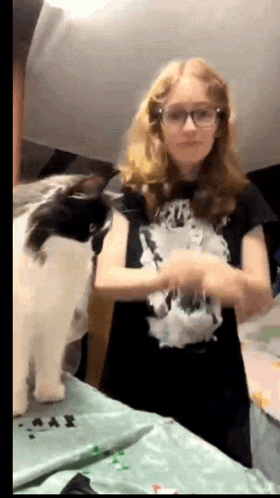 a girl wearing glasses is standing next to a cat .