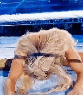 a woman with blonde hair is laying on her back on a wrestling ring