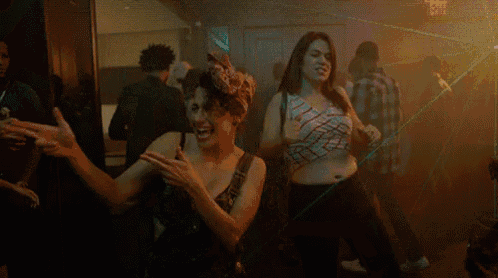two women are dancing together in a dark room in a club .