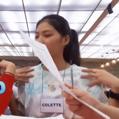 a woman wearing a name tag that says colette holds a piece of paper
