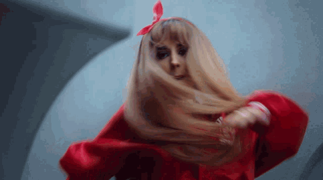 a woman with long blonde hair wearing a red jacket