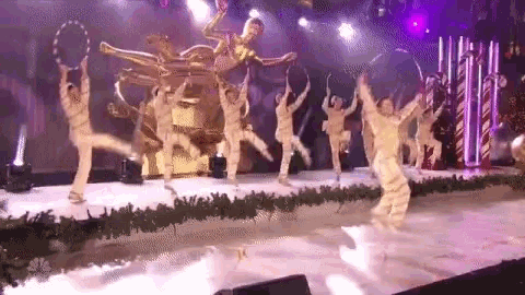 a group of people are dancing on a stage with hula hoops in their hands .