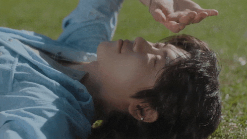 a man in a blue shirt is laying on the grass