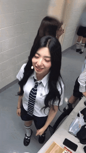 a girl wearing a white shirt and tie with a flower on the collar smiles