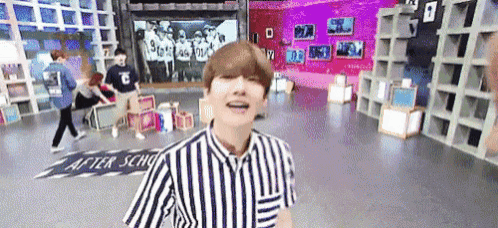 a man in a striped shirt is standing in a room with a sign on the floor that says after school .
