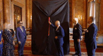 a group of men are standing around a large black cloth in a room