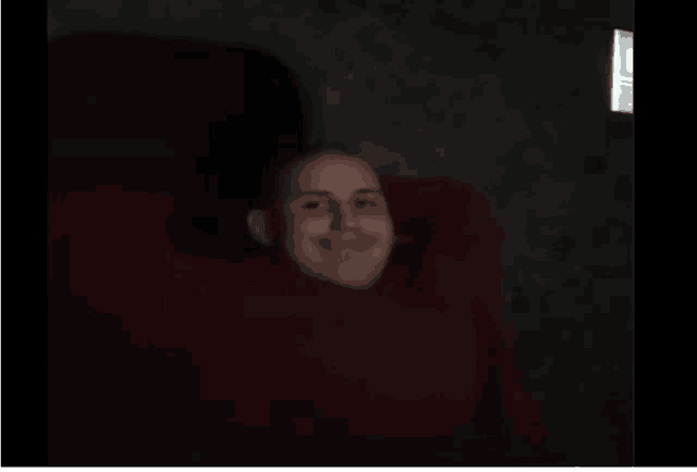 a man laying in a chair with his head in a red blanket