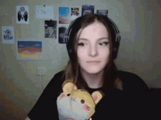 a girl wearing headphones is holding a stuffed animal in her hand .