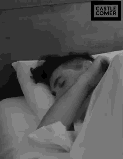 a black and white photo of a person sleeping under a blanket with a castle comer logo in the corner
