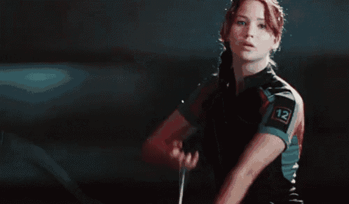 a woman is holding a bow and arrow in a dark room .