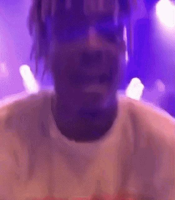 a close up of a man 's face with a purple background and a purple light behind him .